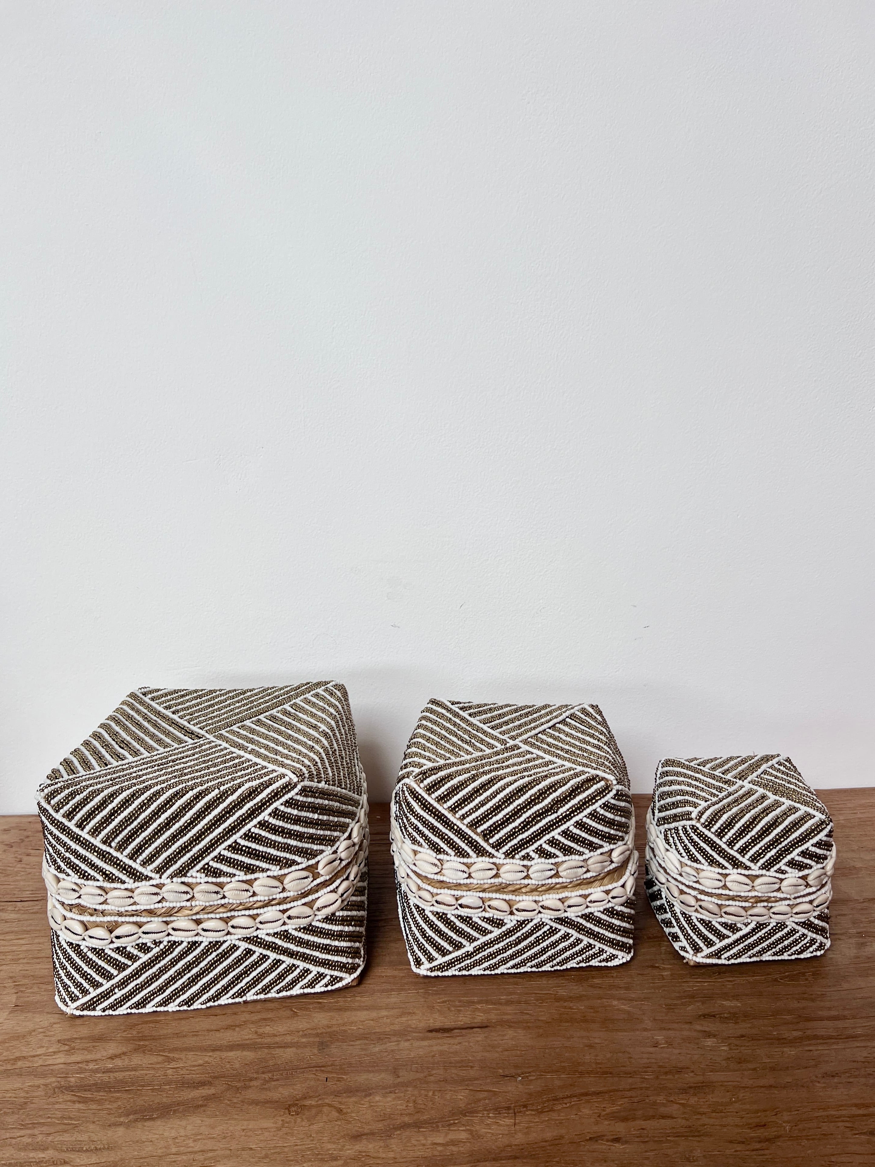 Three woven baskets with geometric patterns on a wooden surface and light gray background