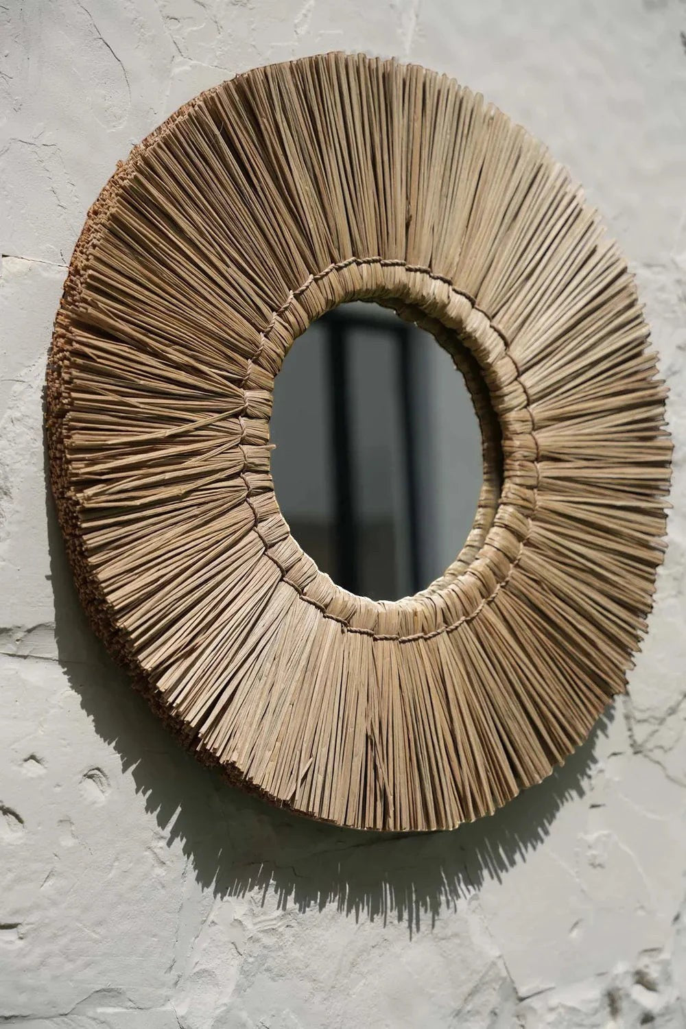 Kayu Living Alang Alang round mirror with natural grass fringe and central reflective glass. Boho coastal wall decor.