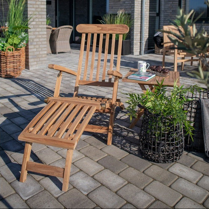 Kayu Living Arrecife natural teak deck chair with adjustable backrest and footrest, set up on a patio.