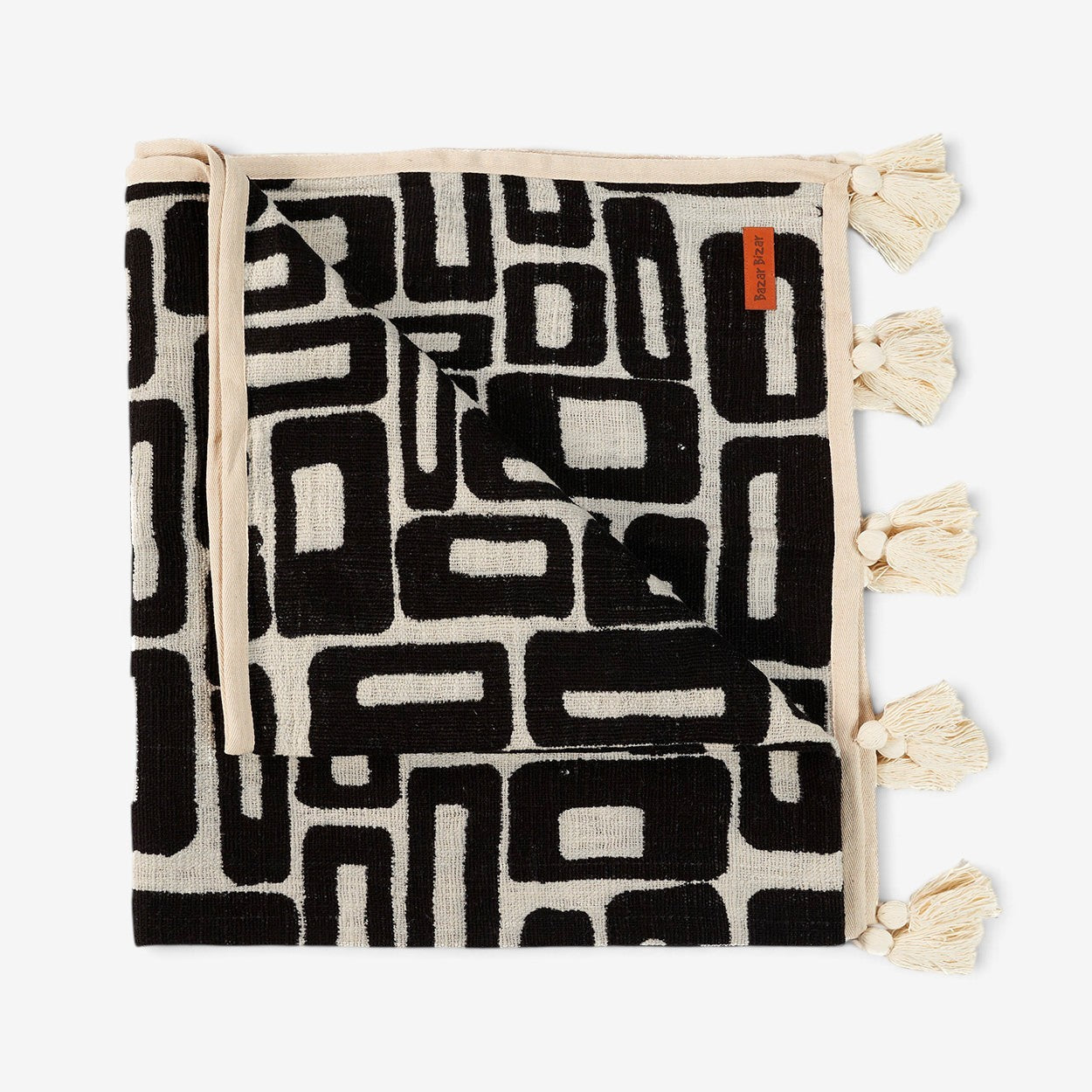 Kayu Living Aztec-pattern cotton bed throw in natural black with decorative tassels and a woven geometric design.