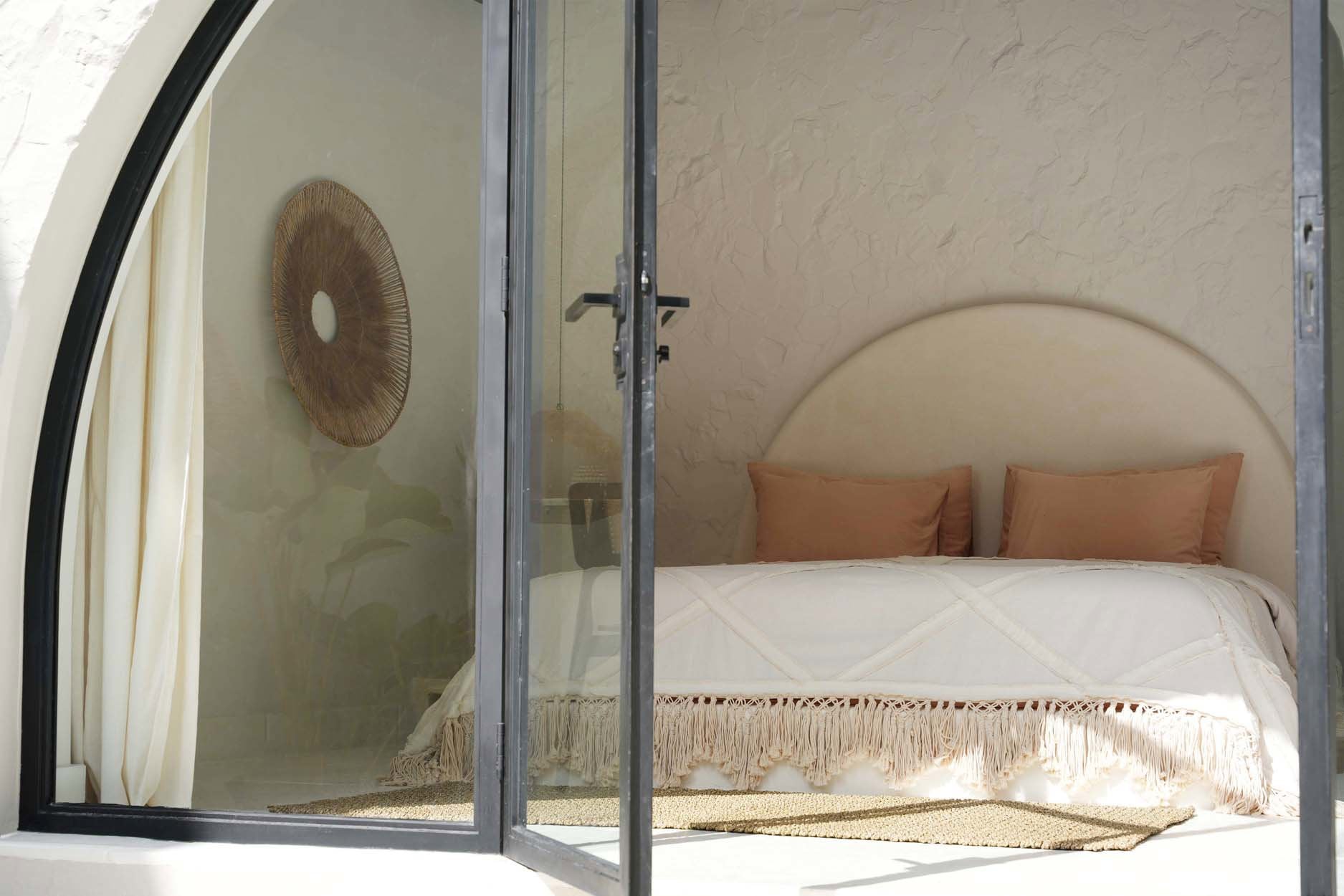 Kayu Living Berber Bed Throw in natural cotton with plush fringe draped over a bed in a serene bedroom setting.