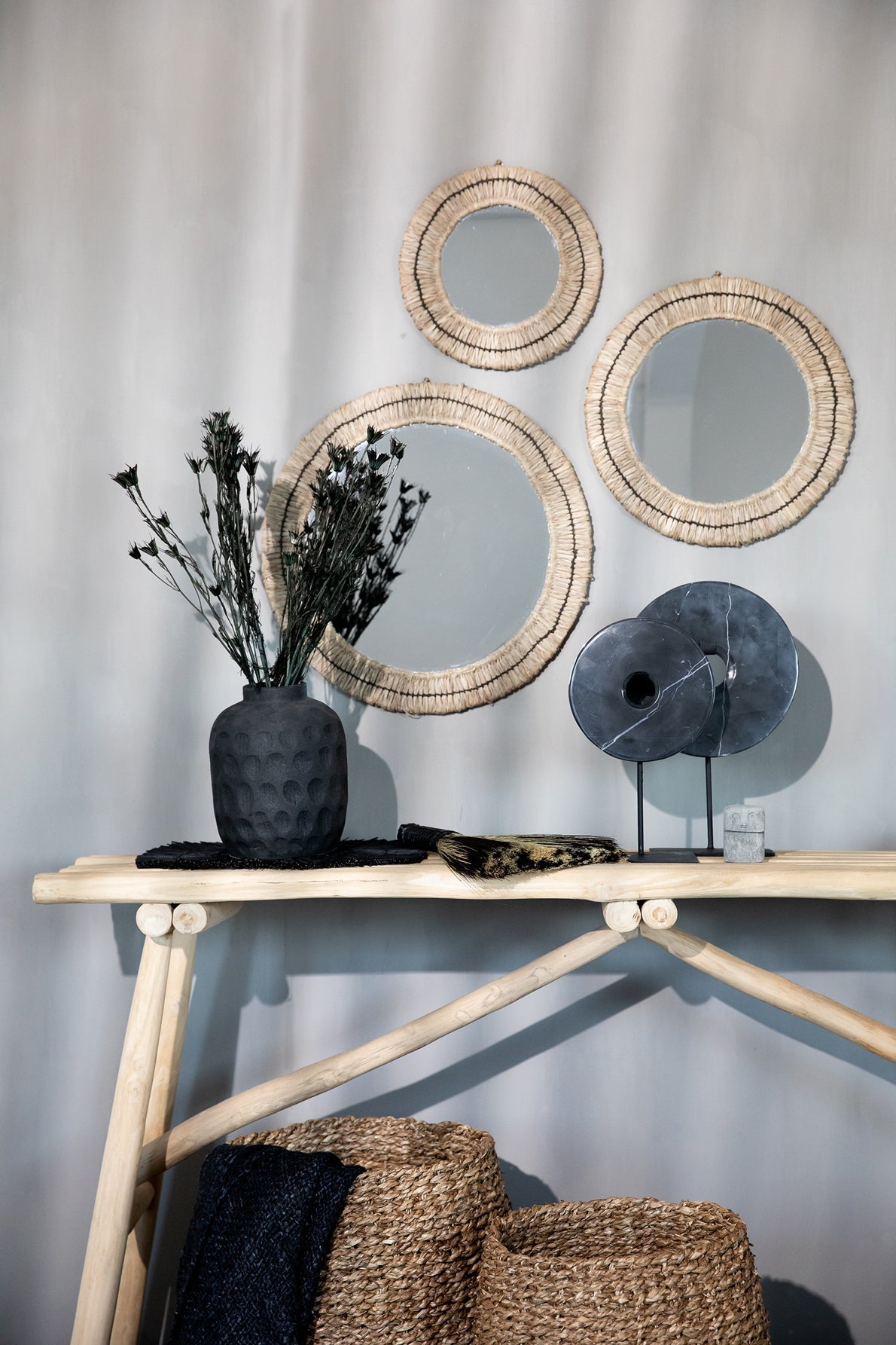 Kayu Living large black marble disc sculpture on a metal stand displayed on a wooden console table with decor.