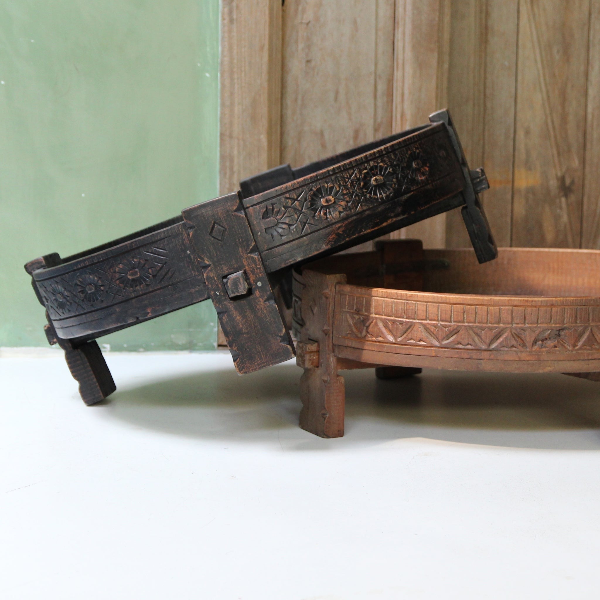 Kayu Living hand-carved black and natural wood Chakki side tables with intricate floral patterns and low profile design.