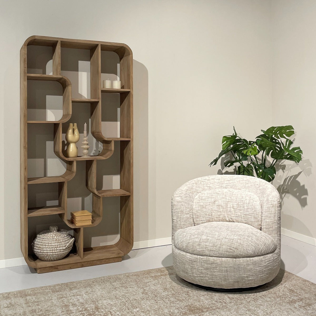 Kayu Living Britt swivel armchair in cream textured fabric, featuring a rounded design next to a wooden bookshelf.