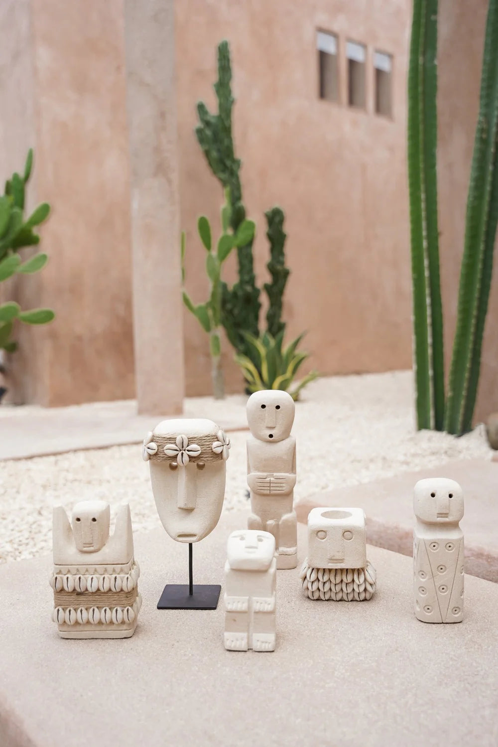 Kayu Living handmade stone gatekeeper figurines in various shapes displayed on a stone surface in a desert setting.