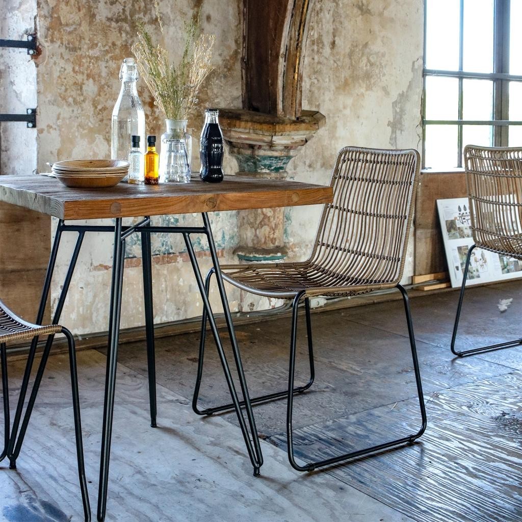 Kayu Living Jane natural synthetic rattan garden chairs with black metal frames in a rustic dining setting