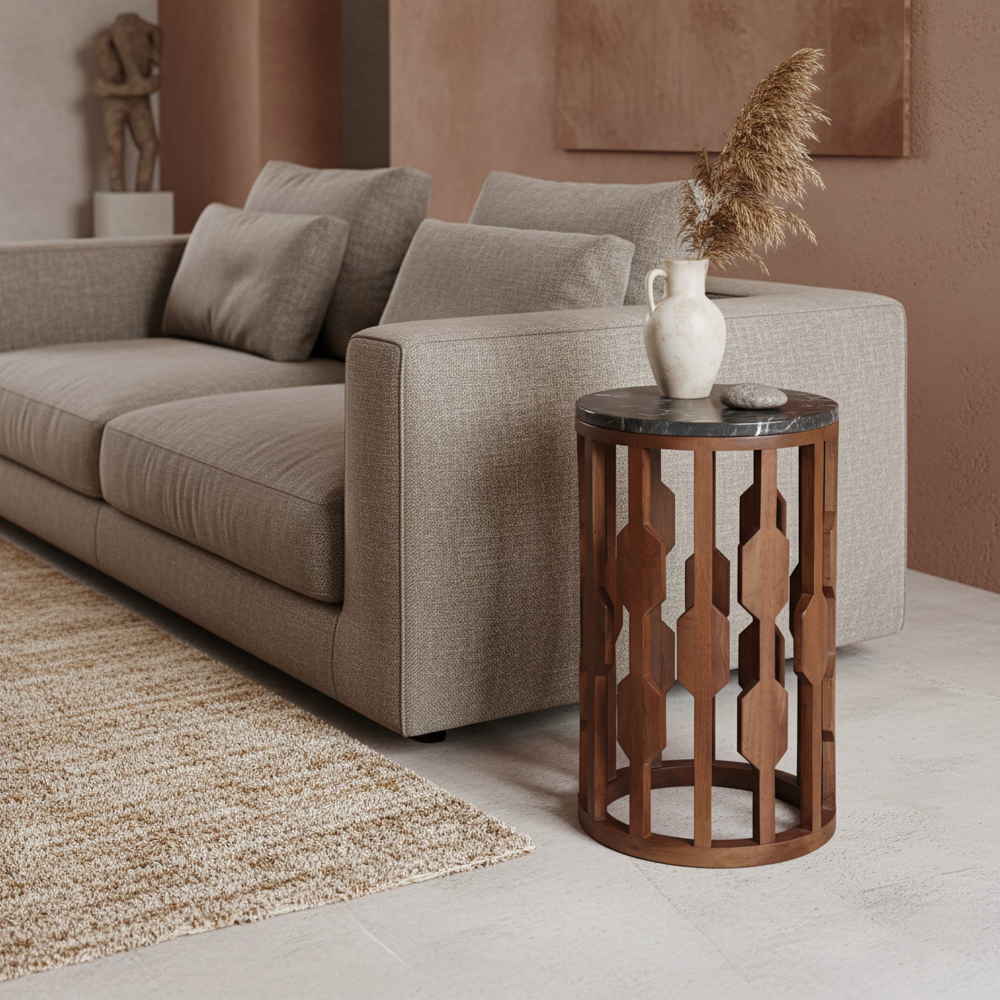 Kayu Living Lampung side table with a round black marble top and intricate dark mango wood base next to a sofa.