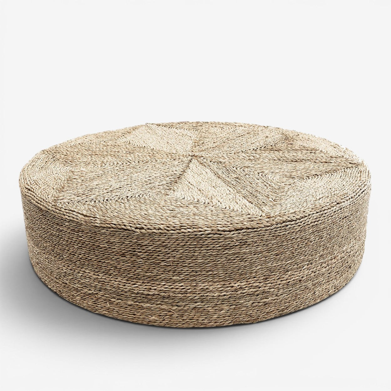 Kayu Living large round seagrass pouf with a textured woven body and geometric patterned top in natural tan tones.
