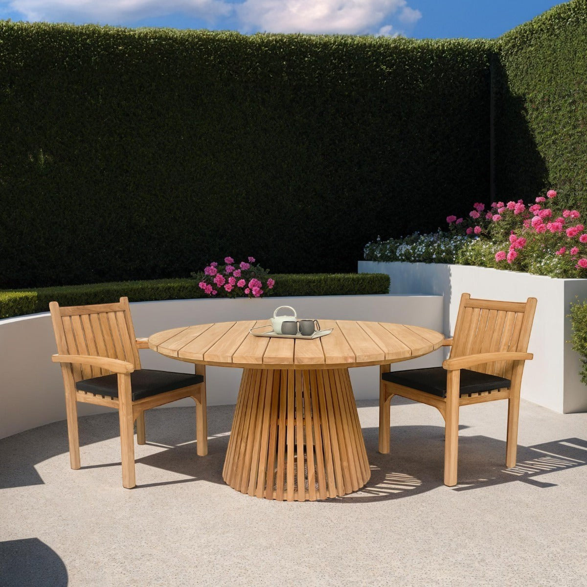 Kayu Living Marco teak chairs with black cushions and matching round slatted table on a sunny patio.