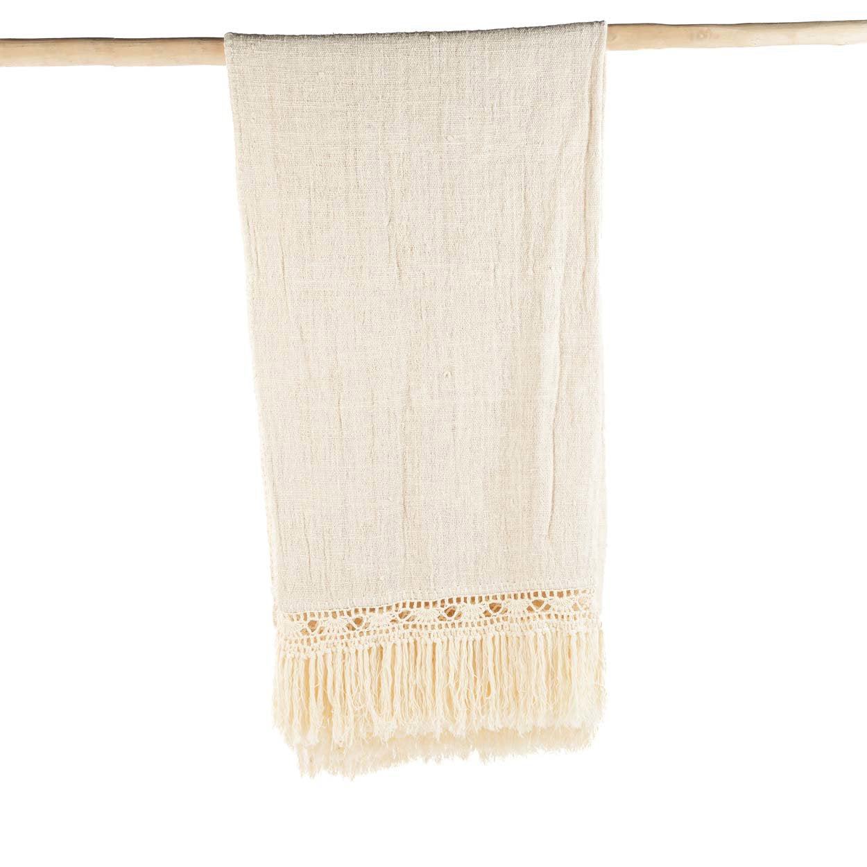Kayu Living Gypsy natural cotton bed throw with intricate crochet detailing and fringe trim hanging on a wooden rail