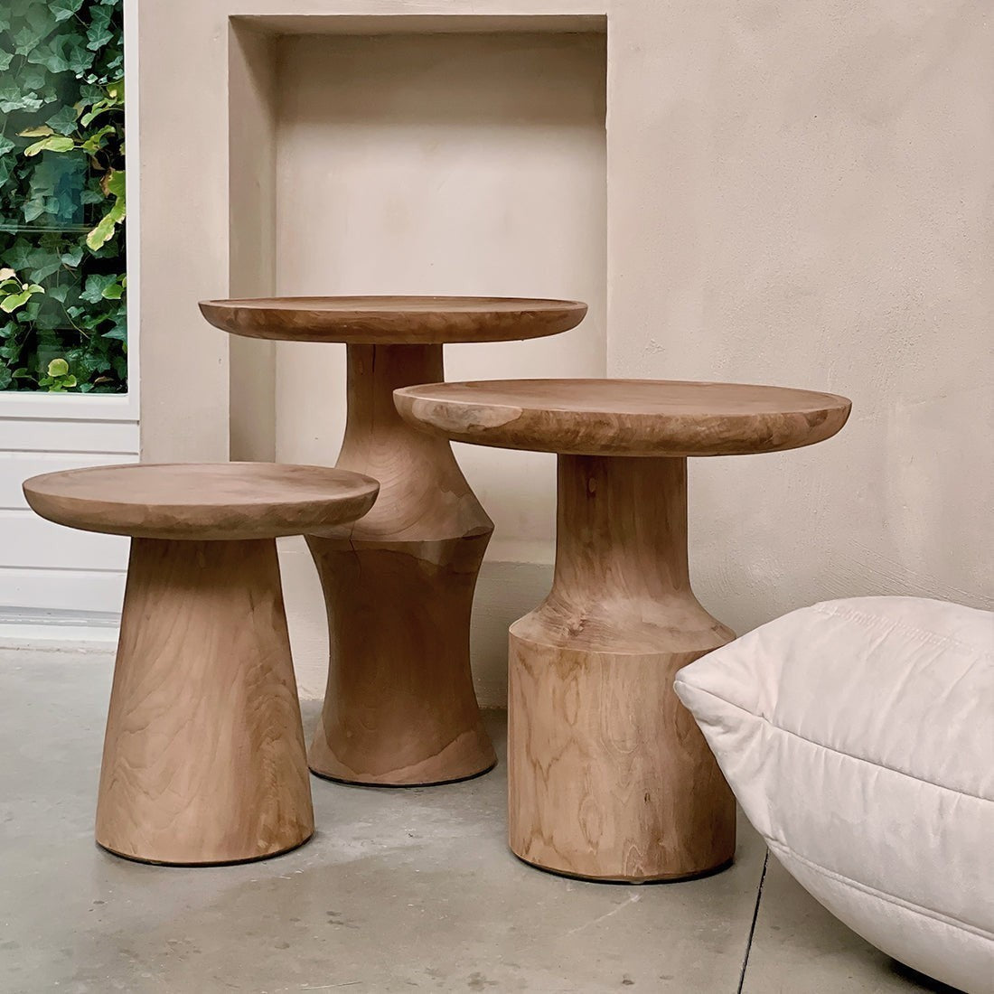 Kayu Living Nero Dawn teak side tables in three varying heights with natural wood grain and modern pedestal bases.