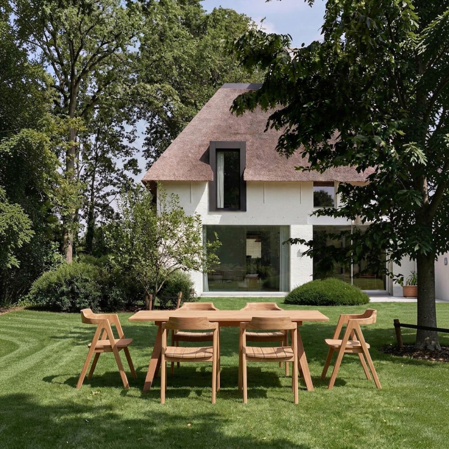 Kayu Living Nihi Sumba outdoor dining chairs and table made of natural teak wood on a green lawn.