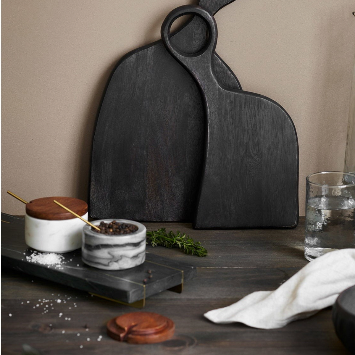 Kayu Living Pauri marble storage jars with brass spoons and wooden lids on a dark wooden kitchen surface