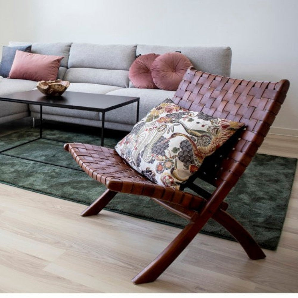 Kayu Living Perugia folding chair in rich brown woven leather with sturdy teak wood legs and a patterned accent pillow