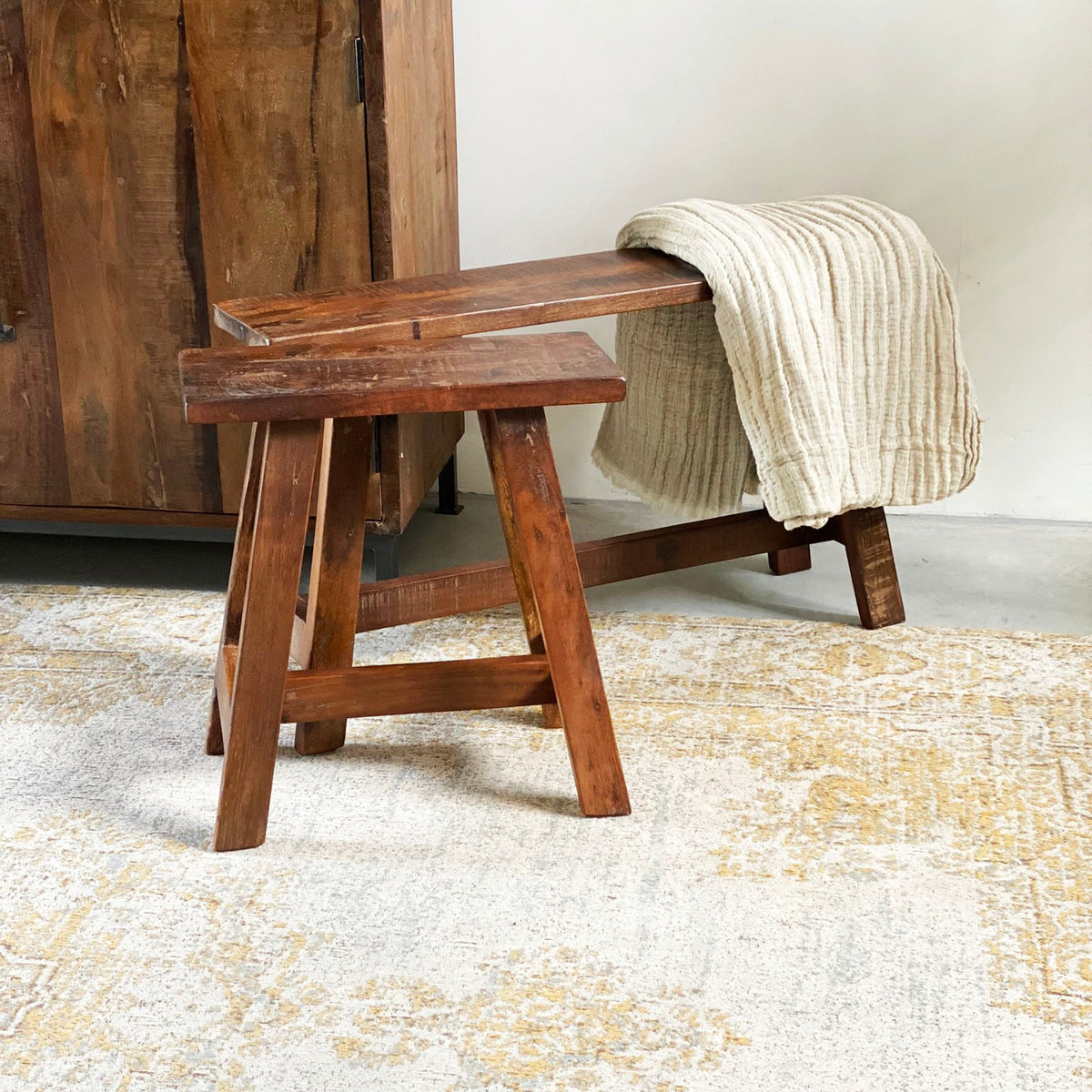 Kayu Living medium factory bus stop bench made of recycled wood with a warm patina, styled with a beige throw blanket.