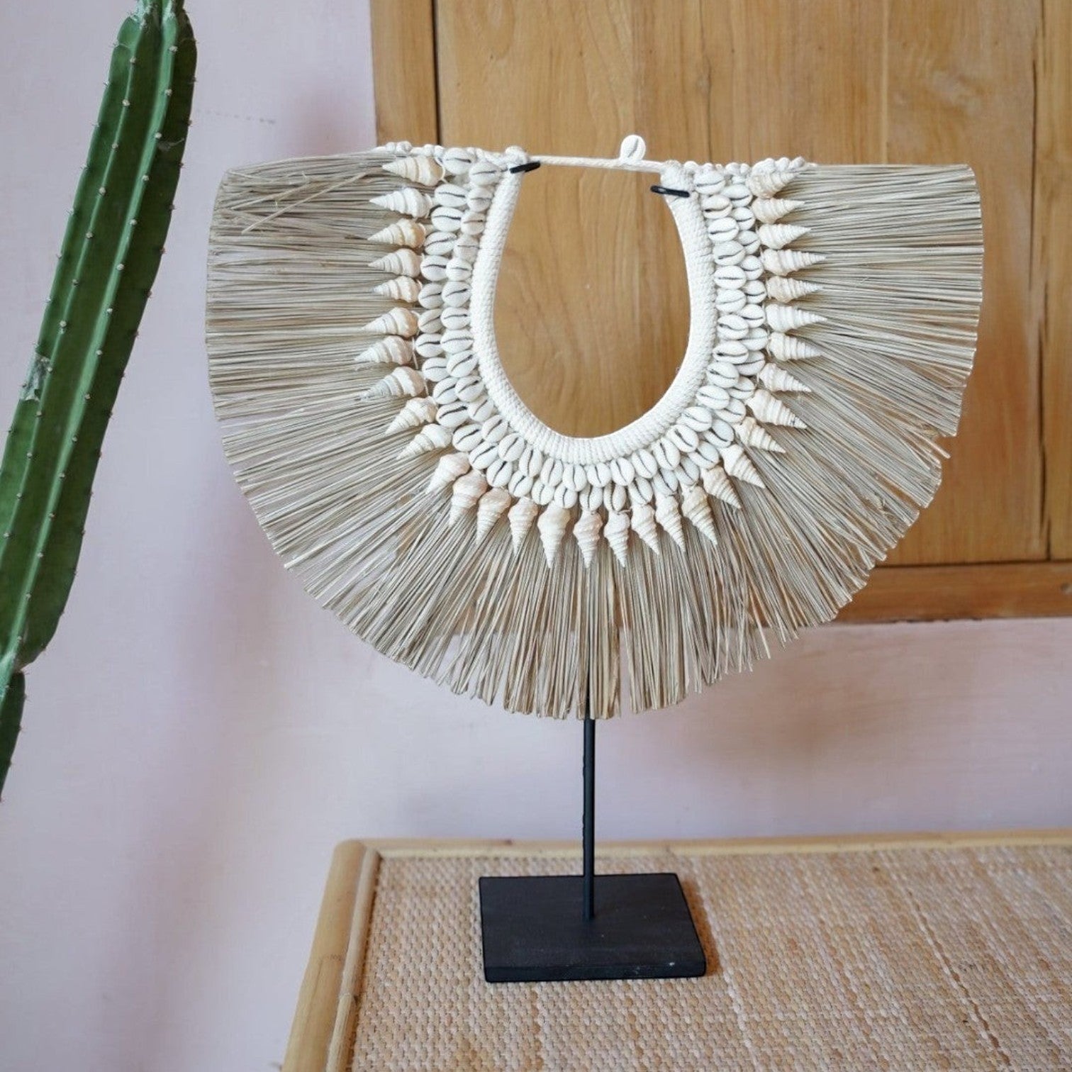 Kayu Living handmade seagrass hanger on a black stand, decorated with natural sea shells in a neutral boho style.