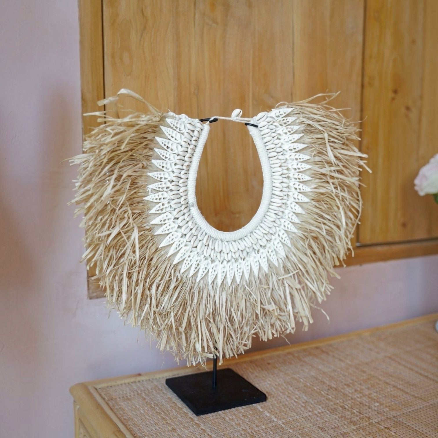 Kayu Living handcrafted seagrass and white shell decorative hanger on a black metal stand for coastal home decor.