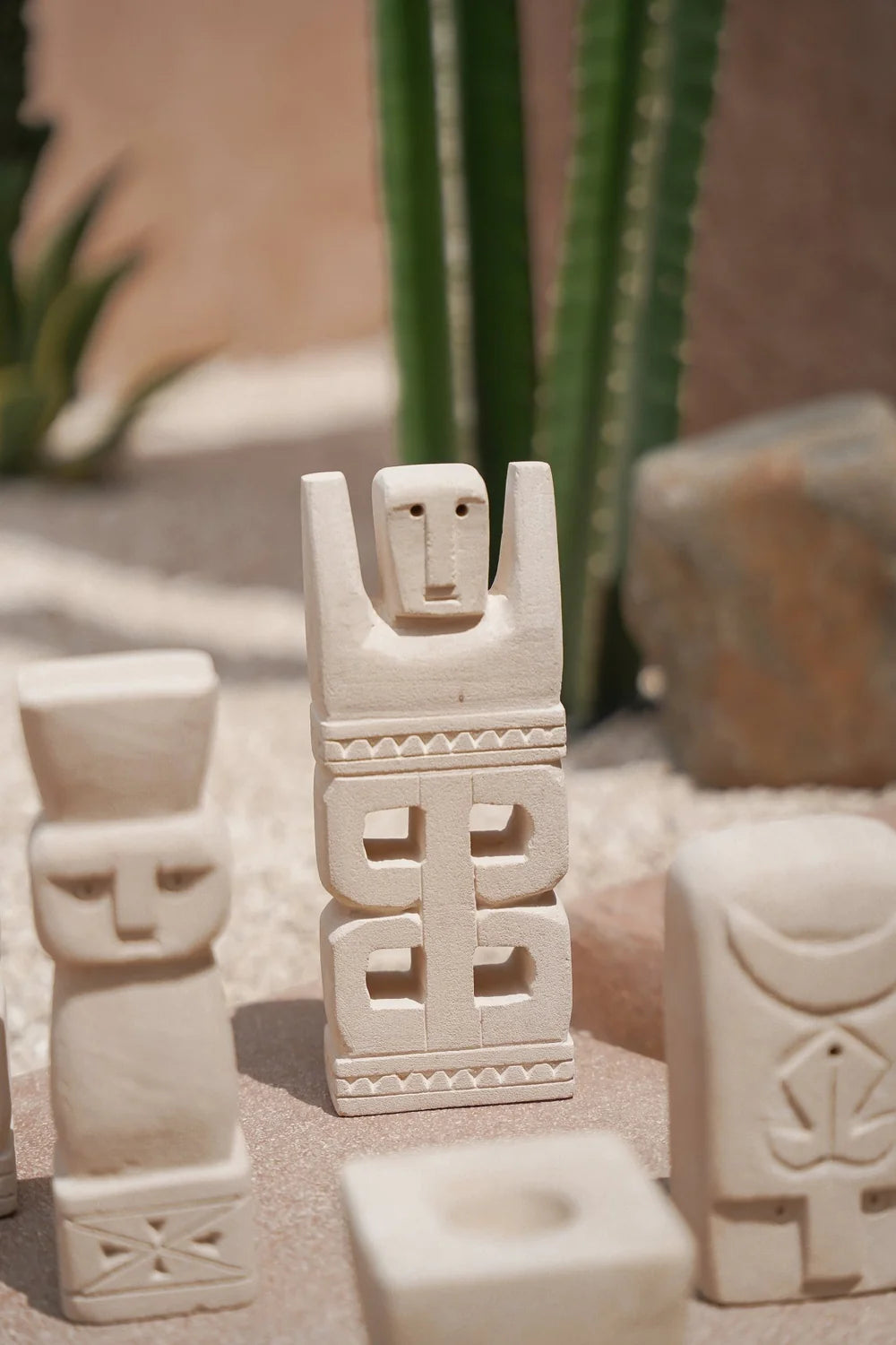 Kayu Living hand-carved stone figurine with geometric carvings, natural beige finish, standing in a desert setting.