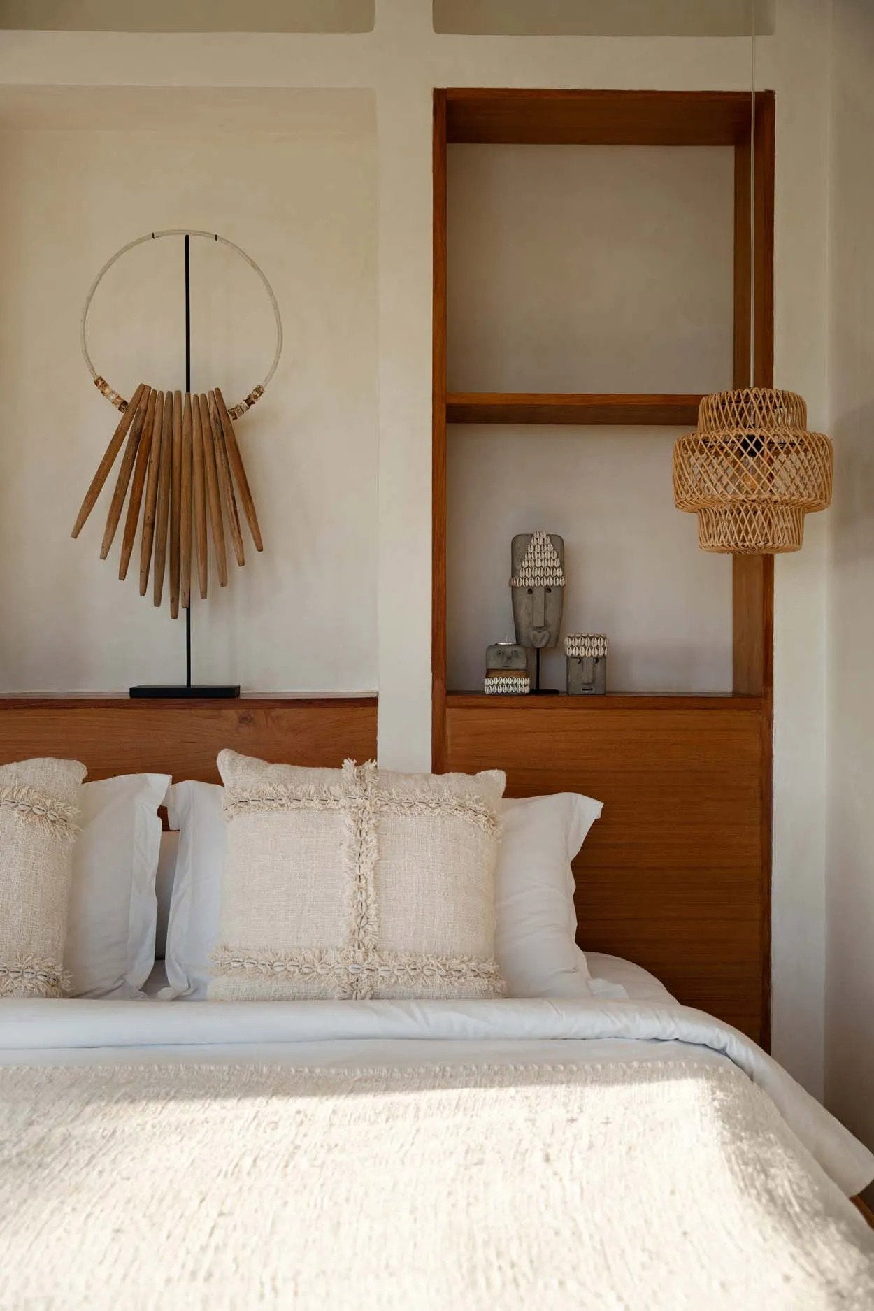 Kayu Living hand-carved grey sandstone Sumba stone statue on a stand displayed on a wooden bedroom shelf.