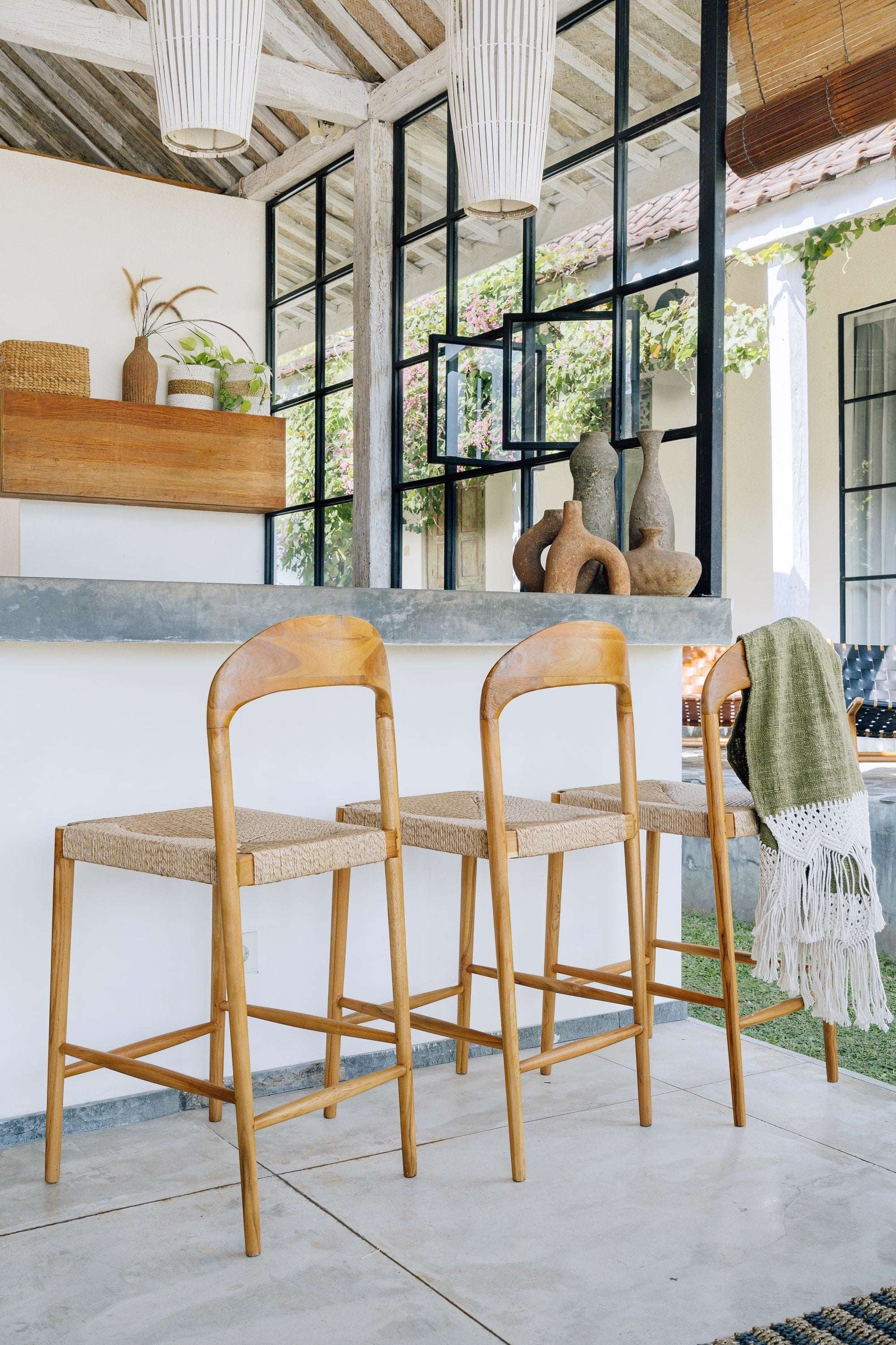 Kayu Living Cemagi teak and natural rope counter stool with curved backrest, perfect for indoor/outdoor use.