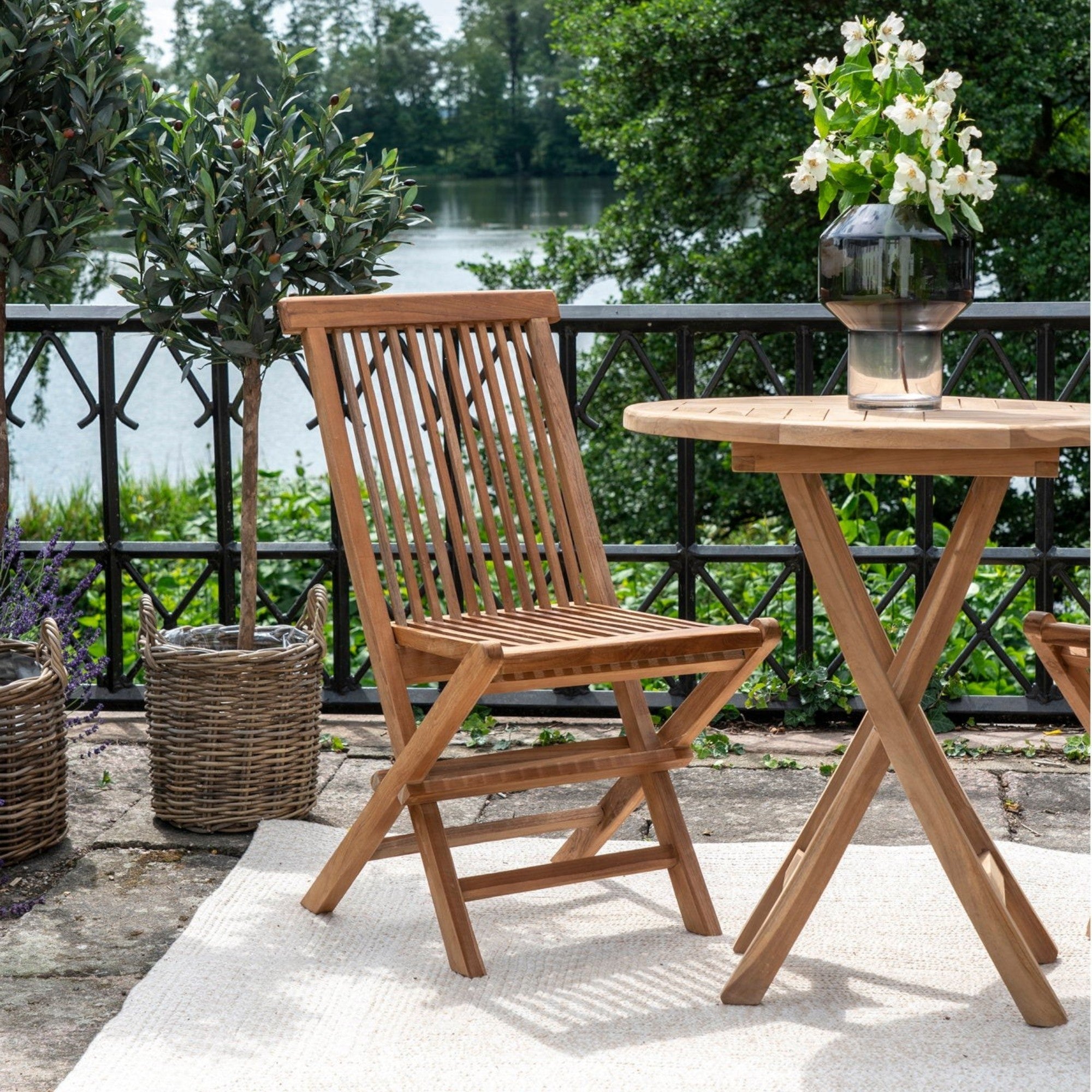 Kayu Living Toledo natural teak wood folding dining chair on a patio with a matching table and garden setting
