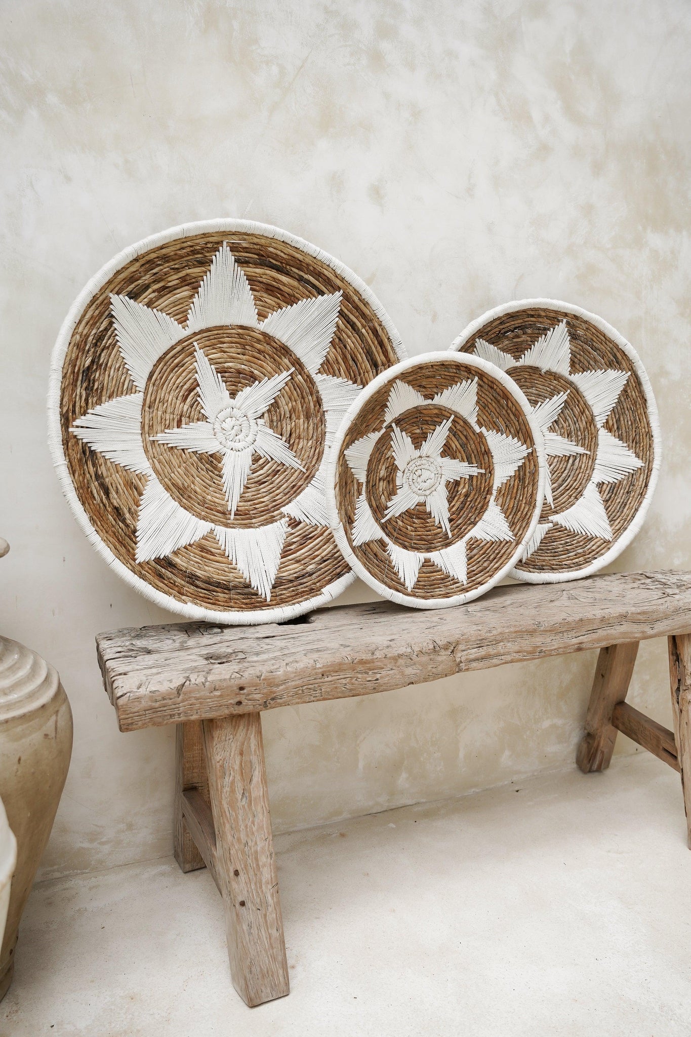 Kayu Living Uluwatu handmade banana leaf and cotton wall baskets in brown and white with star patterns on a wooden bench