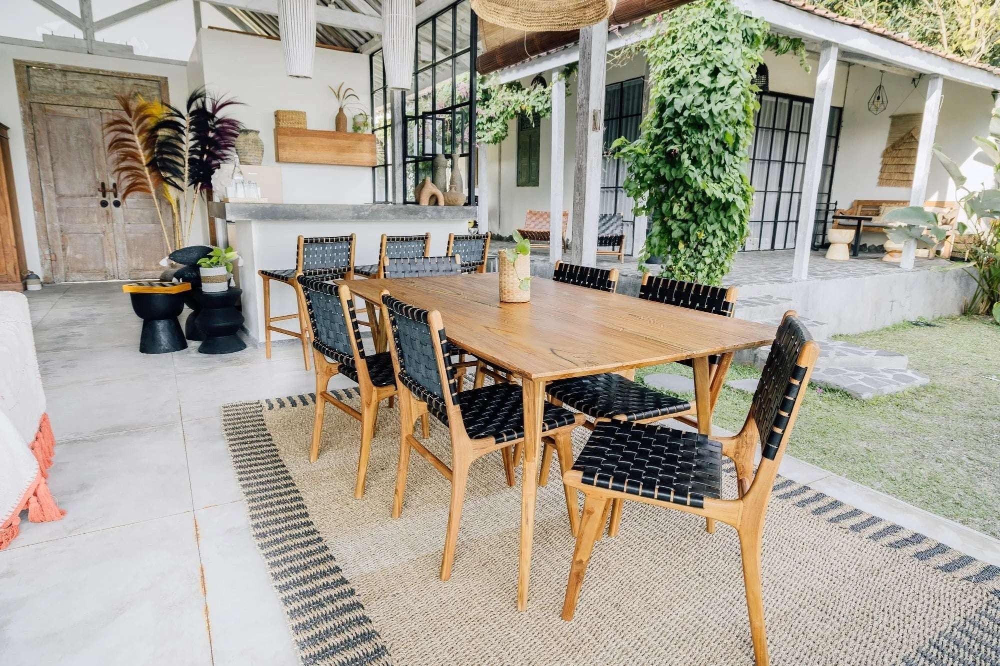 Kayu Living Umalas dining chair with hand-woven black leather seat and teak frame. Modern design, traditional craftsmanship.