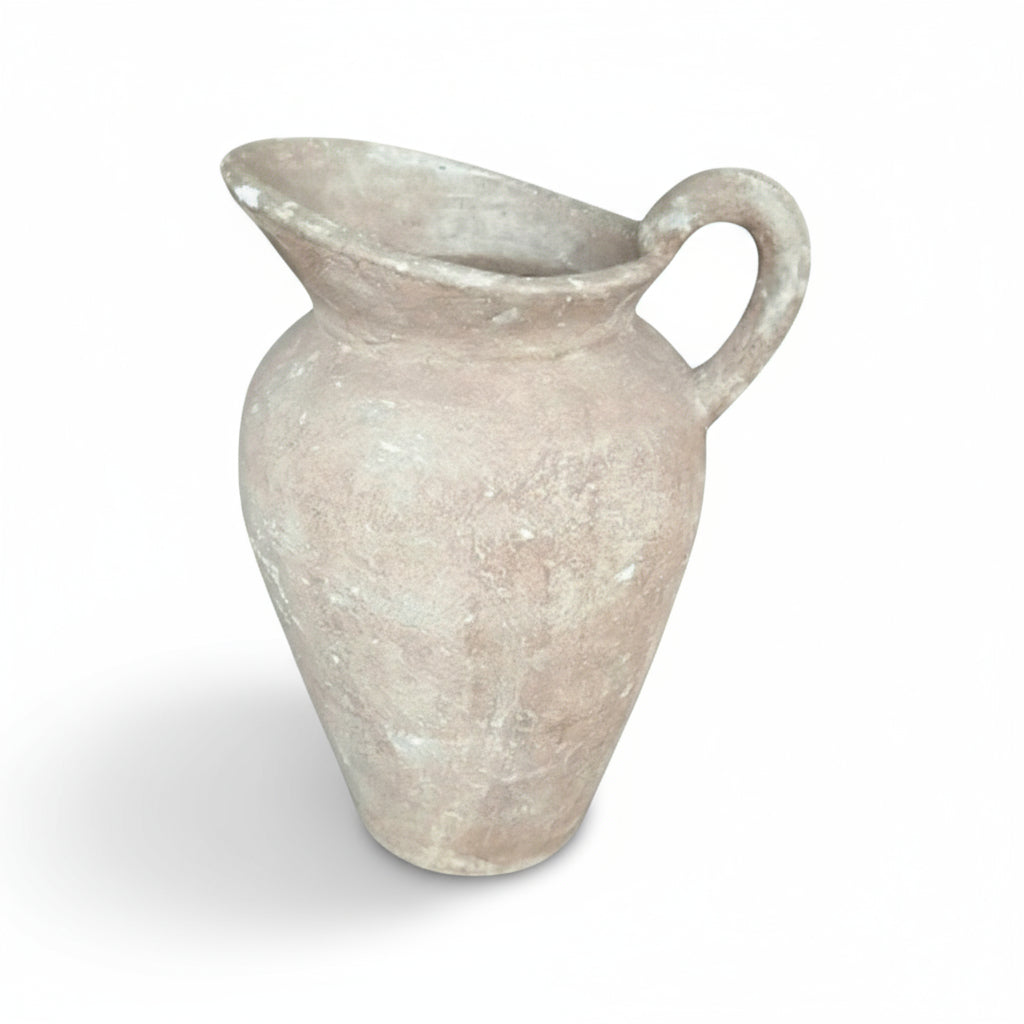 A vintage style terracotta pot with natural variations in texture and color, with a single handle and a flared top.