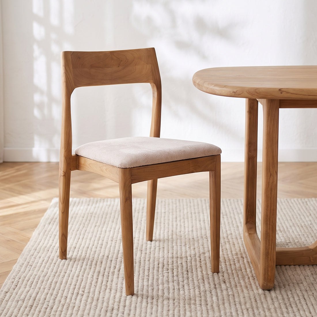 Set of two Raw Materials Freya teak dining chairs in cream with sleek wooden legs and modern design.