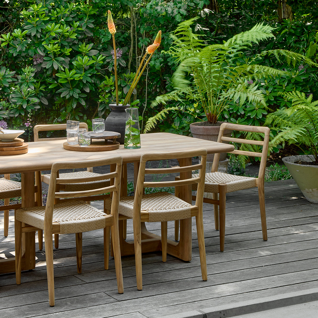 Pair of Raw Materials Verano teak dining chairs with armrests, showcasing sleek wood design and comfortable seating for dining rooms.