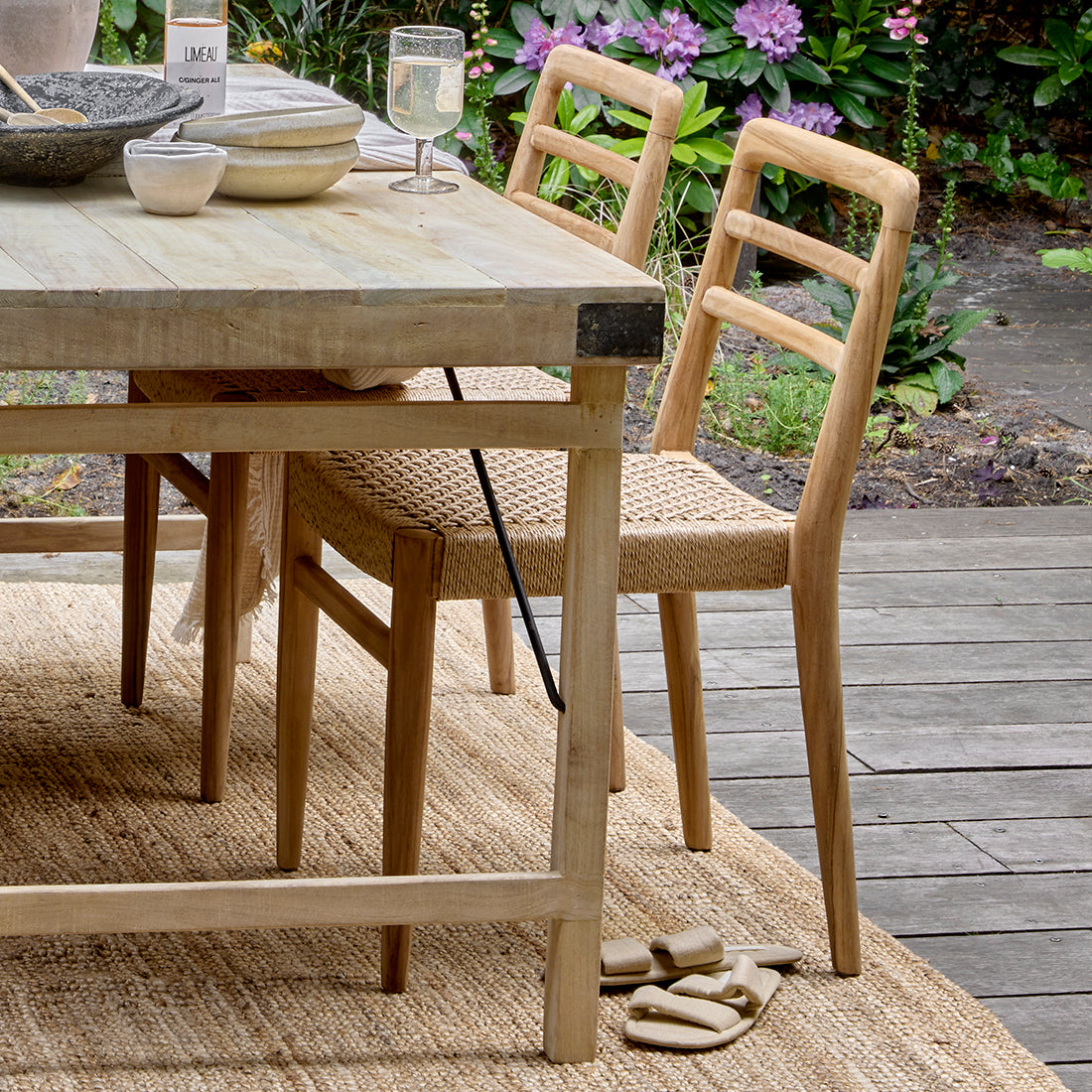 Set of two Raw Materials Verano teak dining chairs with armrests, showcasing sleek wood design and comfortable seating.