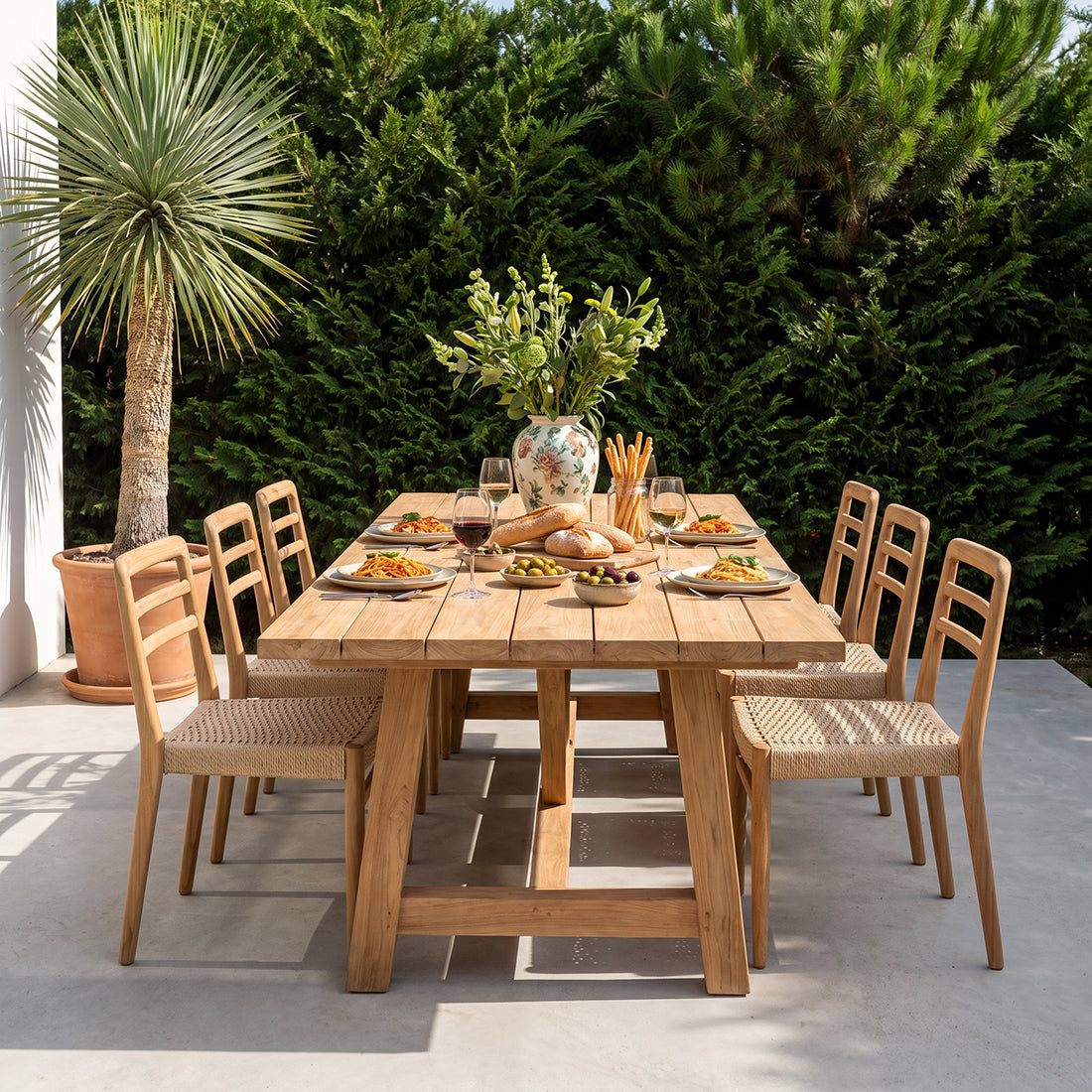 Set of two Raw Materials Verano teak dining chairs with armrests, showcasing sleek wooden design and comfortable seating.