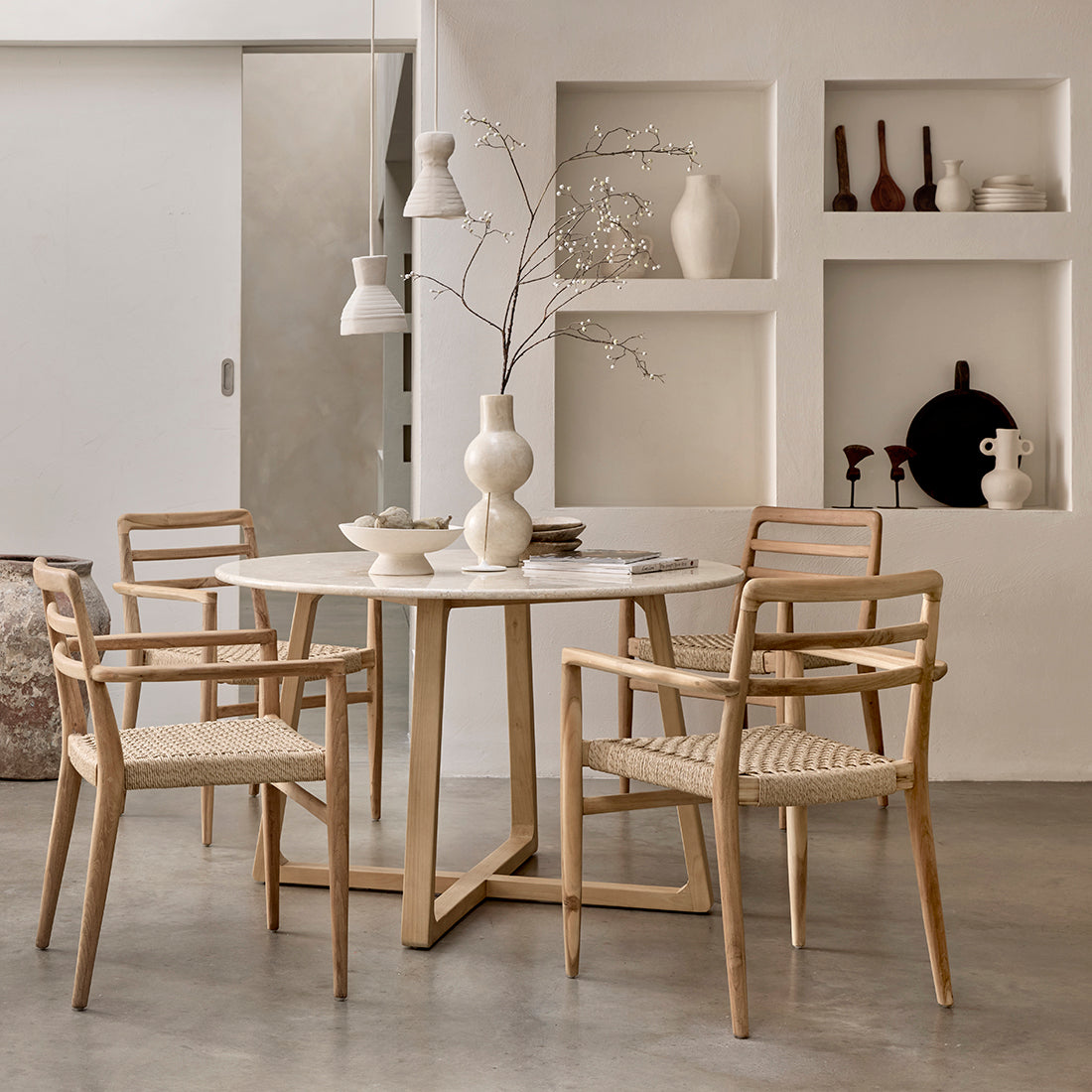 Set of two Raw Materials Verano teak dining chairs with armrests, showcasing sleek wooden design and comfortable seating.