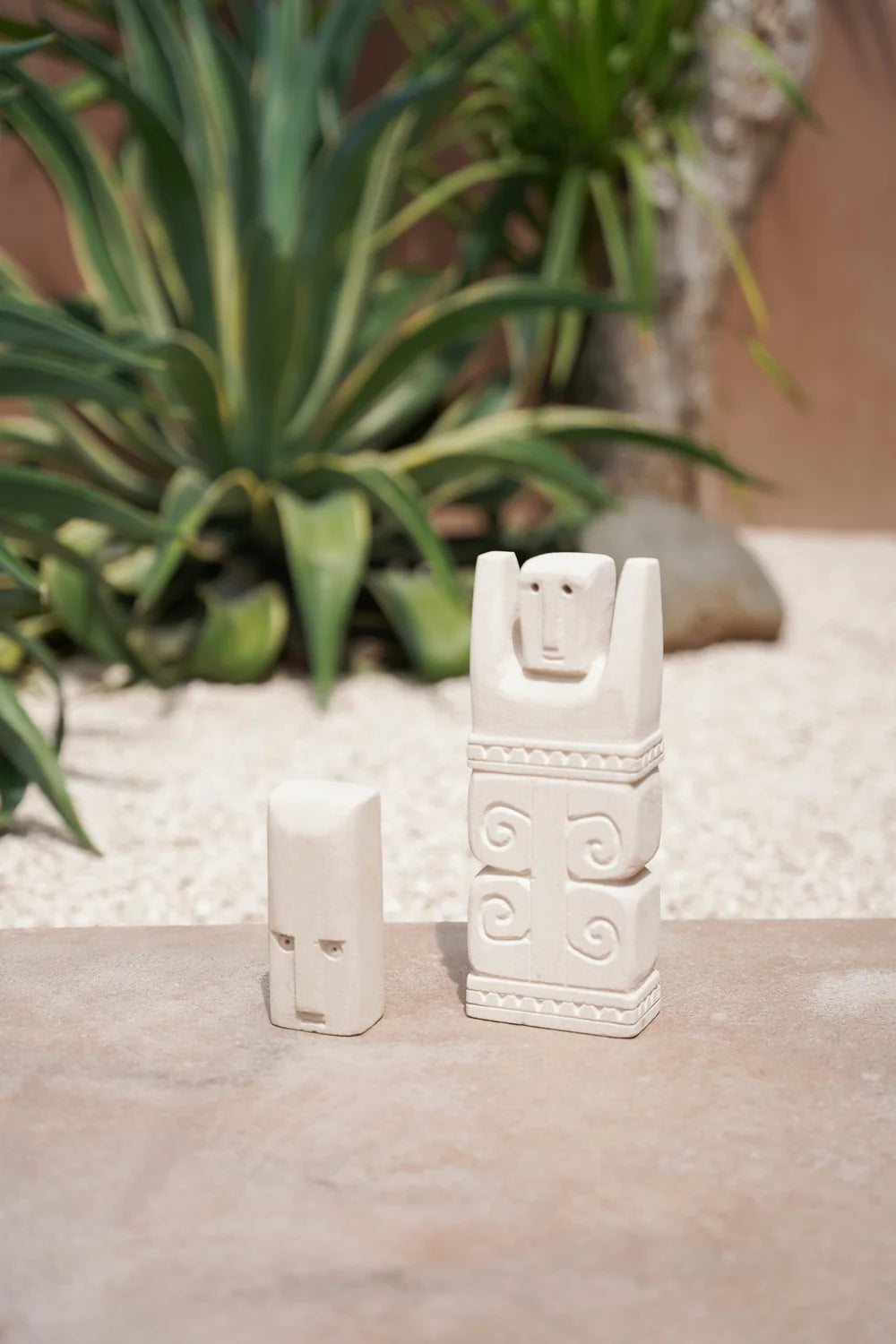 Kayu Living handcrafted Balinese stone figurines featuring a small head and a tall carved guardian figure.