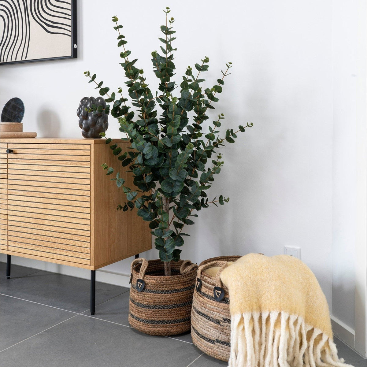 Kayu Living set of two handcrafted natural banana-leaf baskets with black woven stripes and leather handle details.