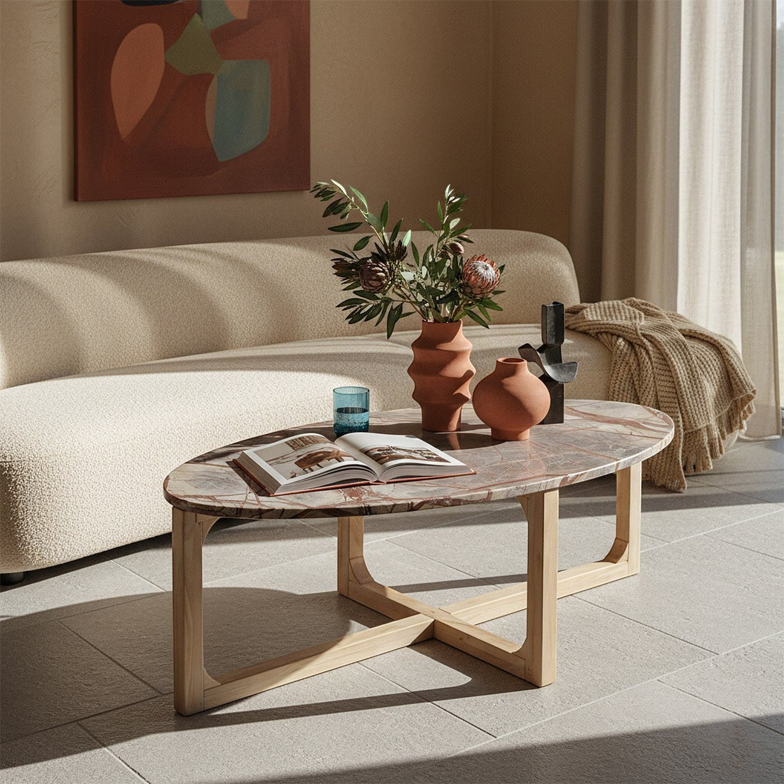 Kayu Living Bizar oval marble coffee table with a veined stone top and light mango wood cross-frame in a living room.