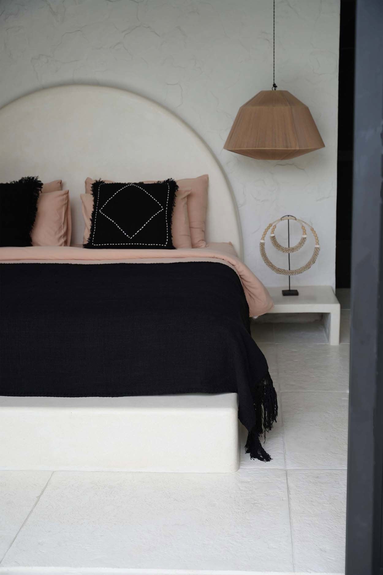 Kayu Living black cotton Gypsy bed throw with fringe detail draped over a modern minimalist bed in a bedroom