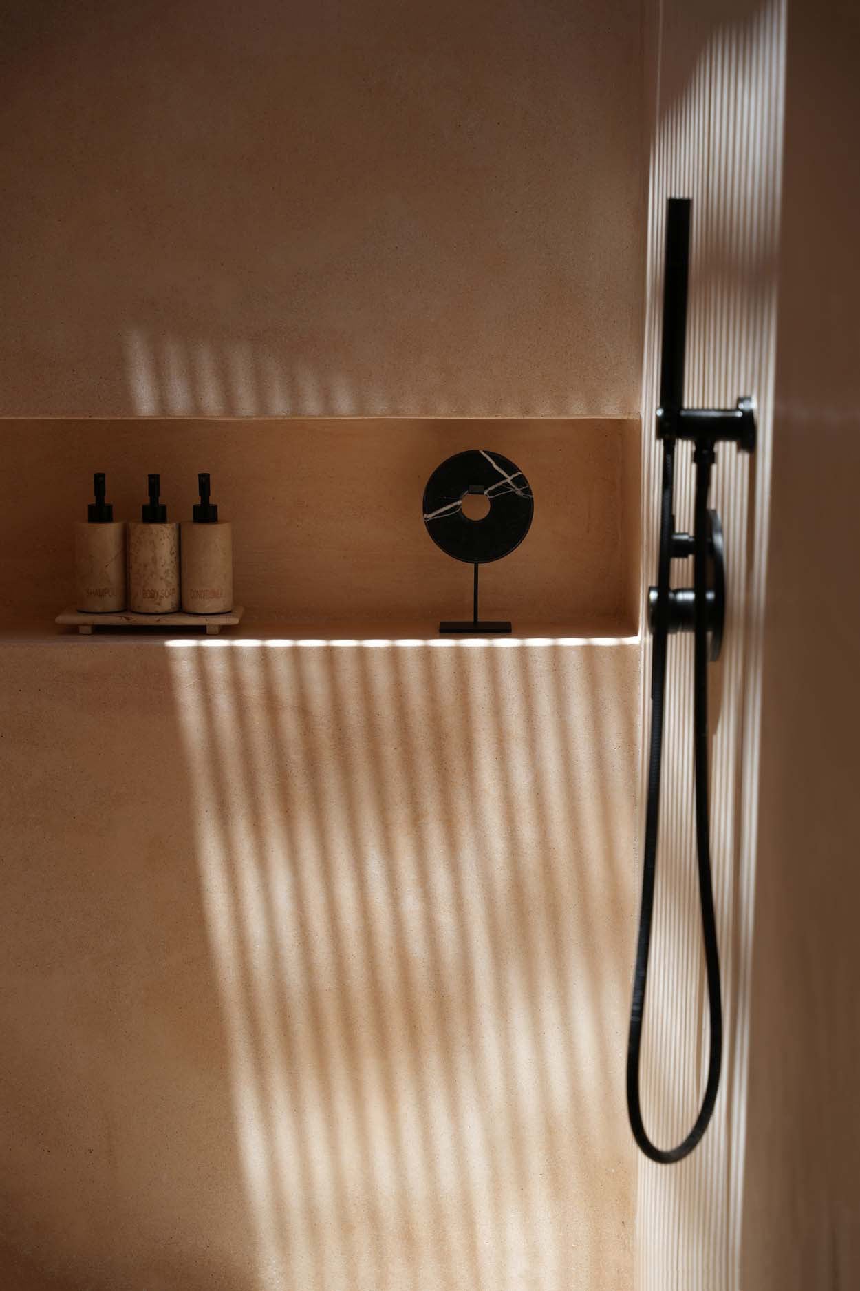 Kayu Living medium black marble disc sculpture with white veining on a metal stand displayed in a bathroom niche