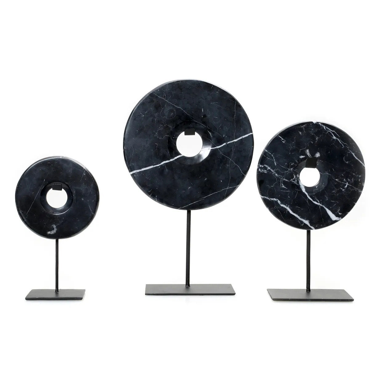 Kayu Living black marble disc sculptures on black metal stands, featuring unique white veining in varying sizes.