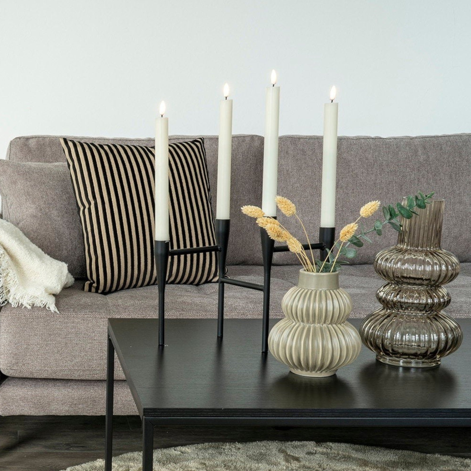 Kayu Living minimalist black steel candle holder with four taper candles on a modern coffee table
