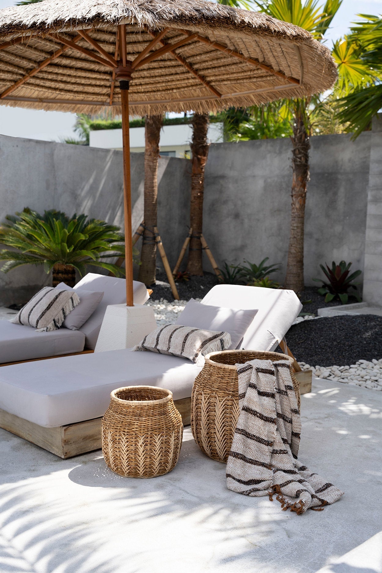 Kayu Living hand-woven Bohemian White cotton plaid throw with fringed edges draped over a wicker basket outdoors.
