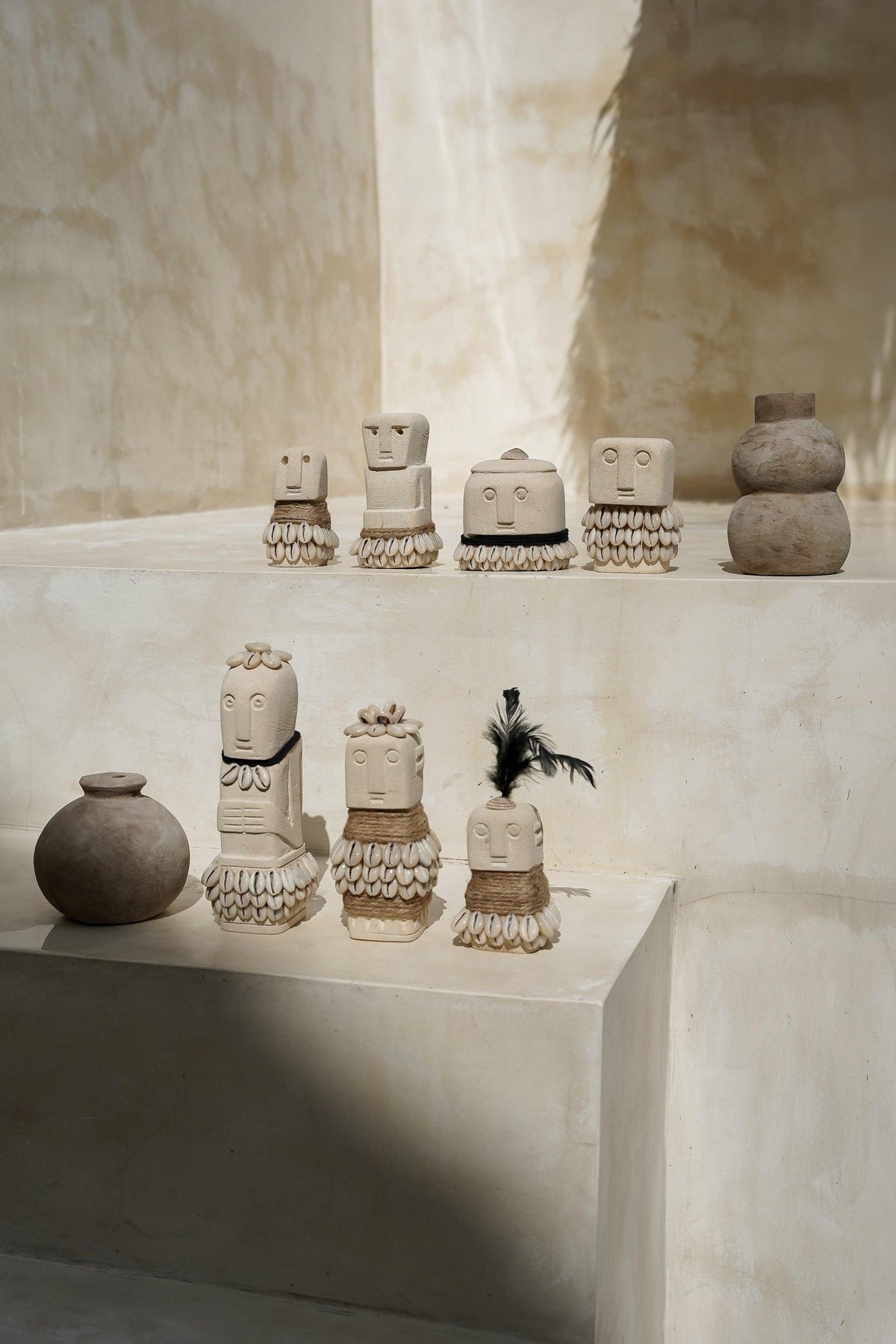 Kayu Living handmade boho stone figurines with shell and rope accents displayed on a tiered beige surface