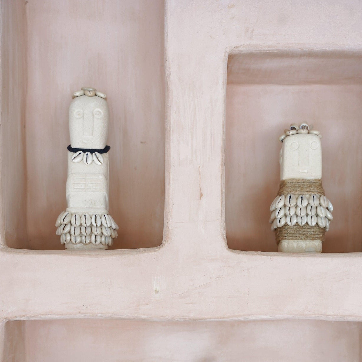 Kayu Living handmade boho stone figurines decorated with shells and feathers displayed in a pink wall niche