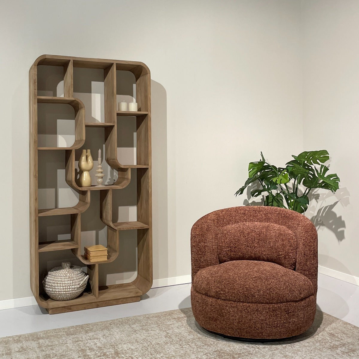 Kayu Living Britt swivel armchair in burgundy textured fabric with a rounded back, placed next to a wooden bookshelf.