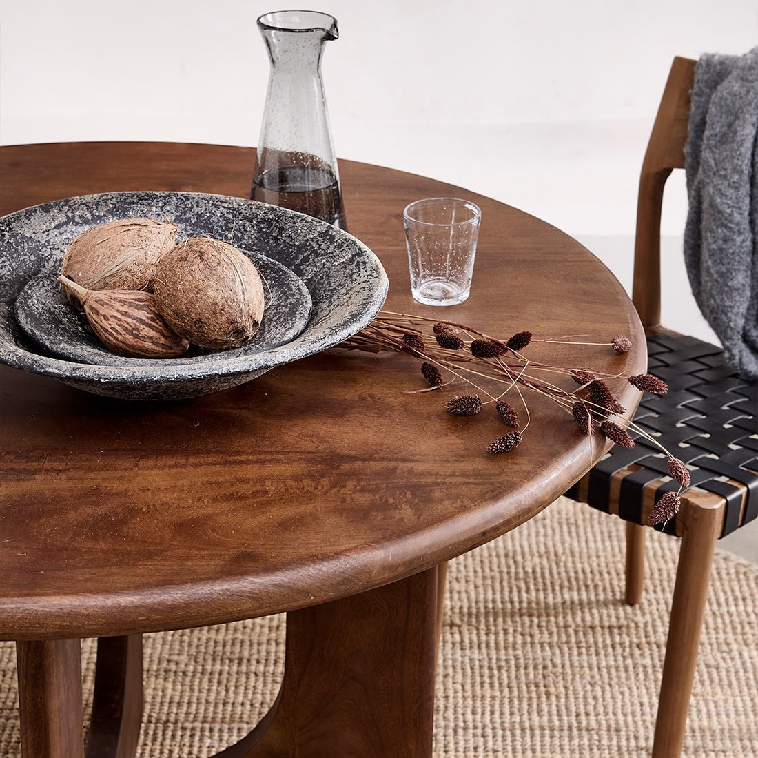 Kayu Living Bullnose Coliseo round mango wood dining table with natural grain, styled with a decorative stone bowl.
