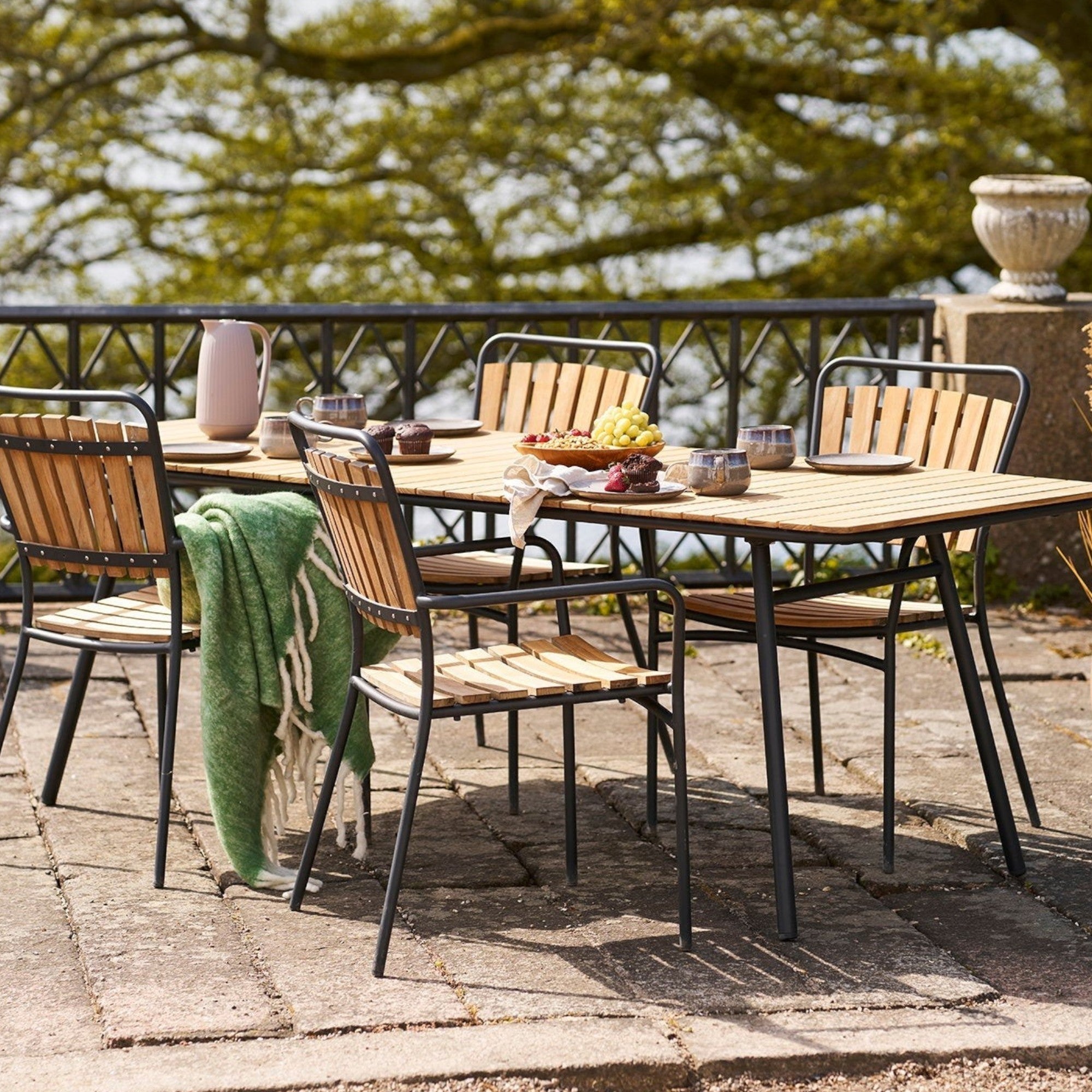 Kayu Living green wool-blend Carmel Plaid throw draped over a wooden outdoor dining chair on a sunny patio