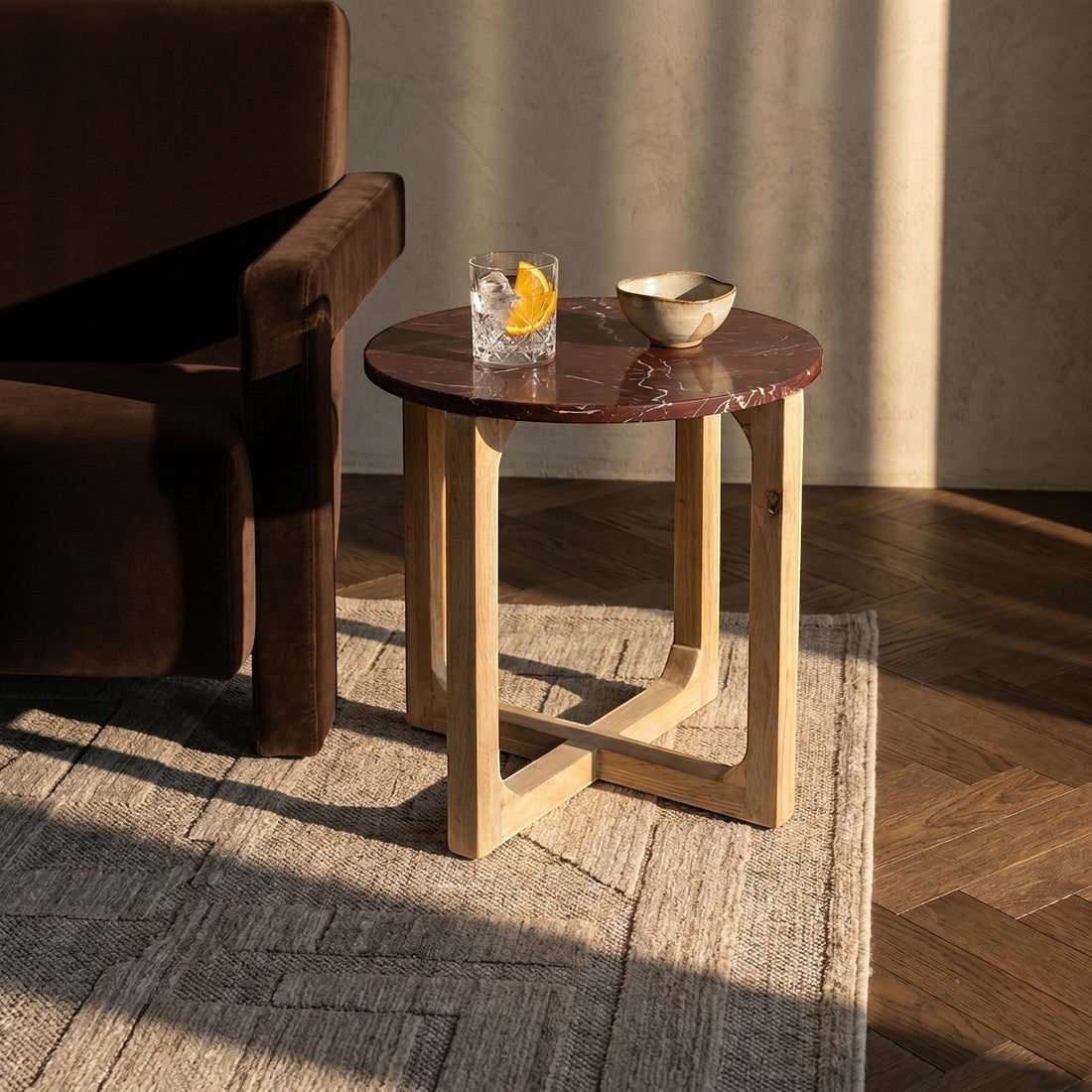 Kayu Living burgundy marble side table with white veins and light mango wood cross-leg base in a sunlit room.