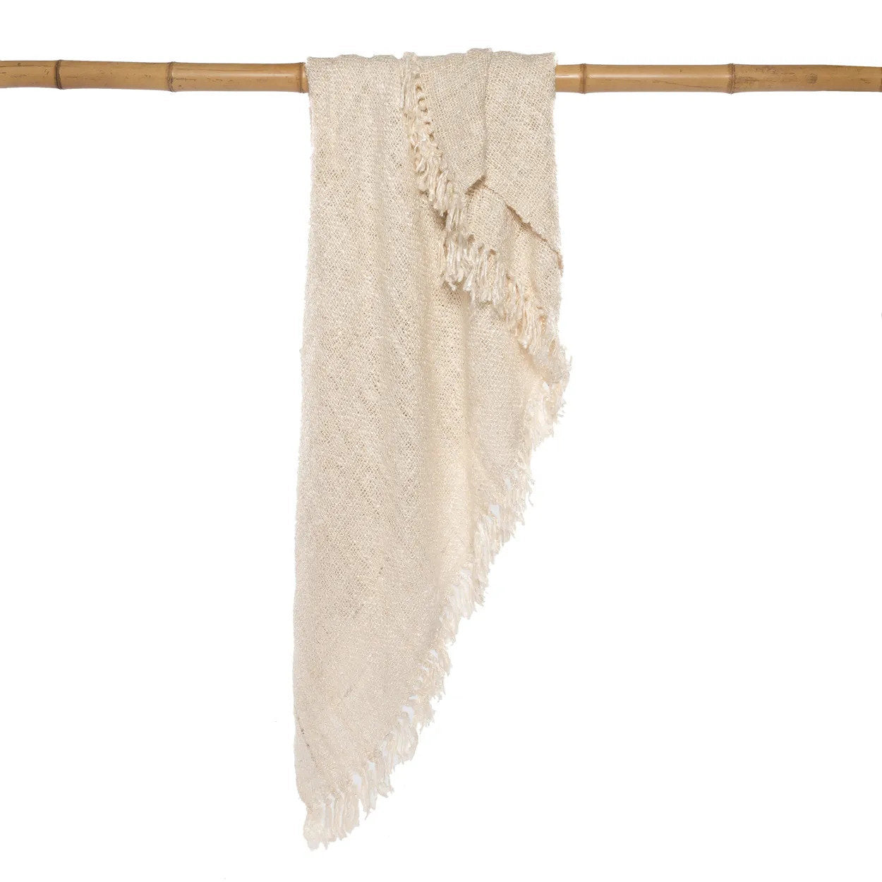 Kayu Living hand-woven cream cotton throw blanket with a waffled texture and fringe edges hanging on a bamboo pole.