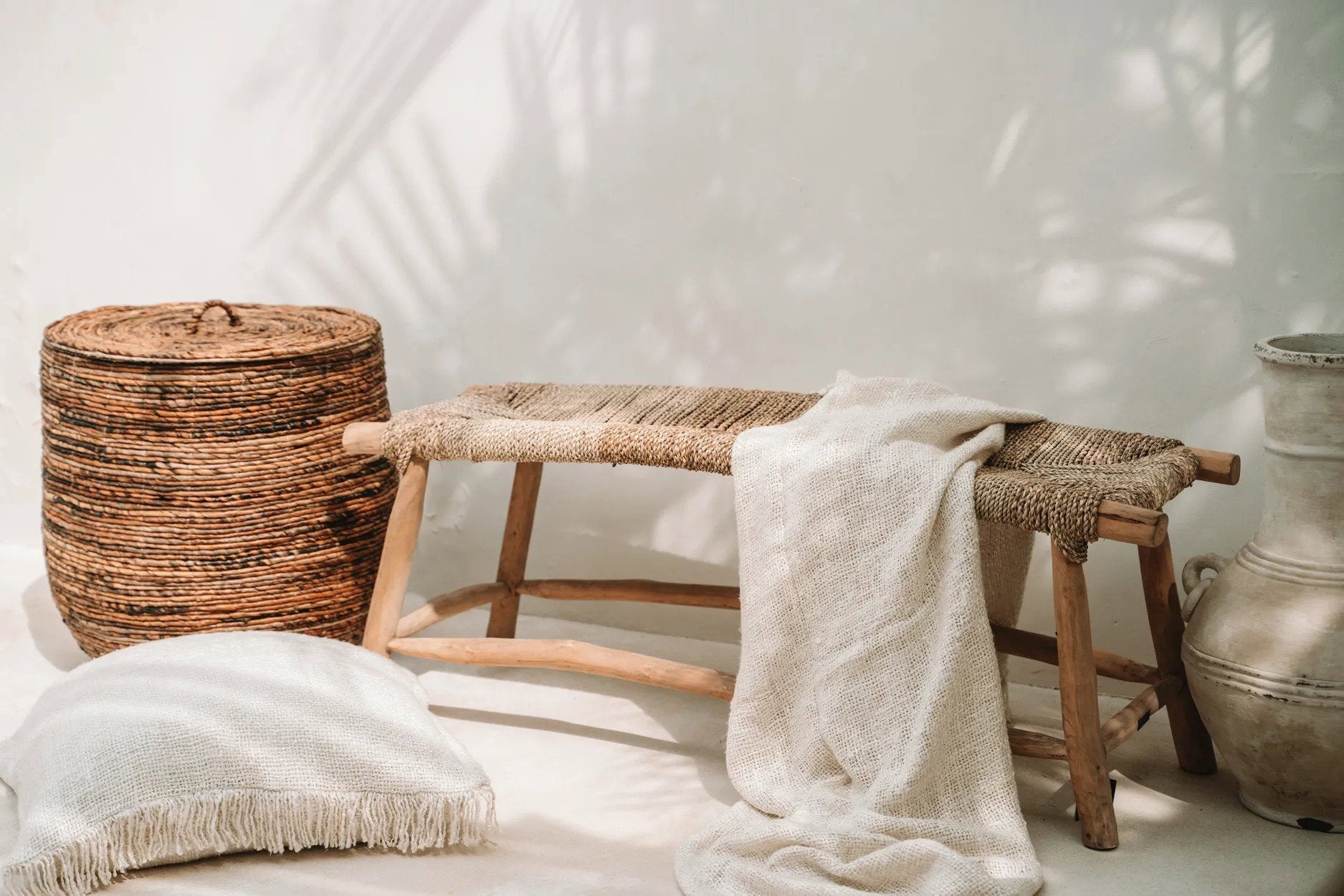 Kayu Living cream hand-woven cotton throw blanket with waffled texture draped over a rustic wooden bench