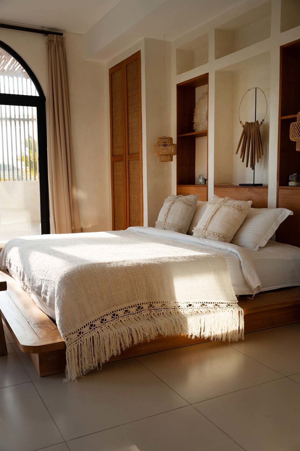 Kayu Living Gypsy bed throw in natural cotton with intricate fringe detail draped over a modern bohemian style bed.